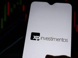 XP Investimentos e gráficos ao fundo