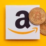 Logo da Amazon e criptomoeda física de Bitcoin