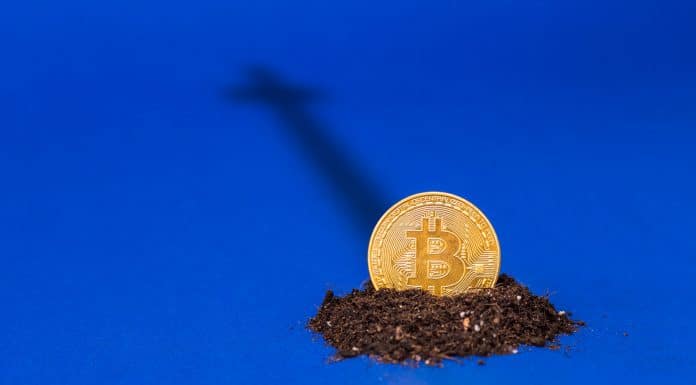 Moeda de bitcoin sobre a terra com sombra de uma cruz