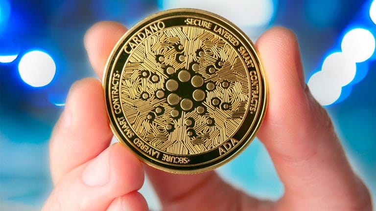 Mão segurando moeda física de Cardano (ADA)