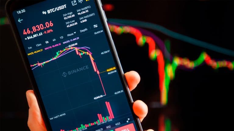 Pessoa segurando celular com Bitcoin em queda