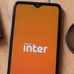 Aplicativo Banco Inter na tela do smartphone, lupa e carteira