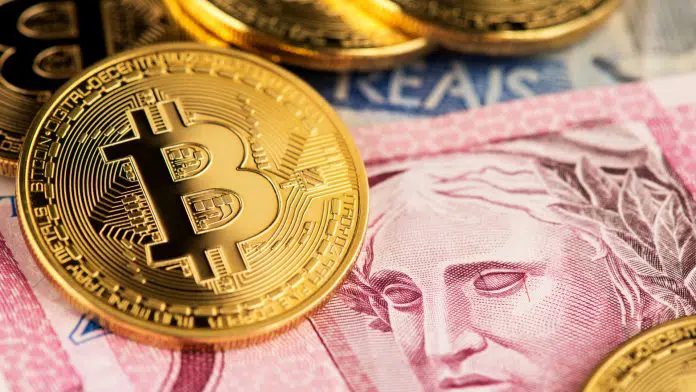 Criptomoeda Bitcoin em notas de dinheiro real brasileiro emitidas pelo BCB