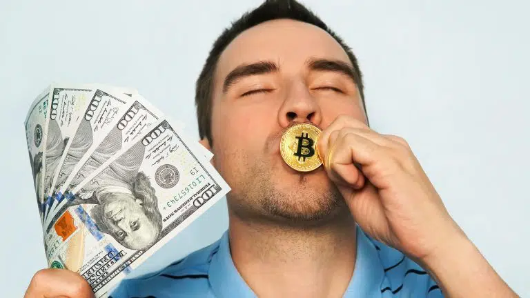 Homem beija Bitcoin em momento de felicidade, com notas de dólar na outra mão