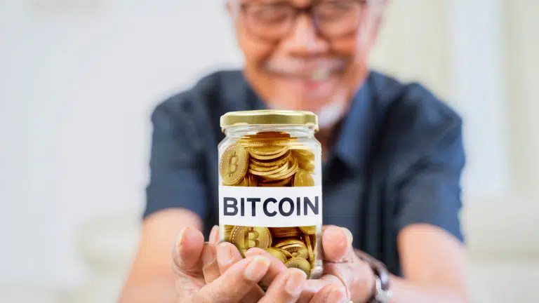 Homem idoso segurando pote com Bitcoin