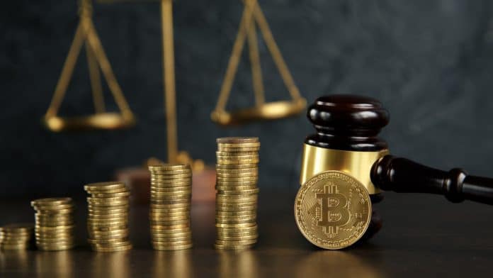 Martelo e balança da justiça próximo de pilhas de Bitcoins