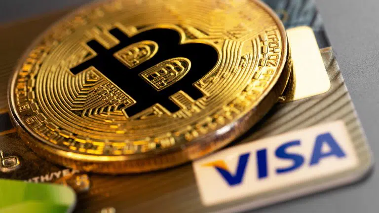 Moeda Bitcoin e cartão com bandeira da Visa e criptomoedas