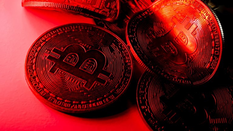 Moedas torcidas com símbolo de bitcoin na luz vermelha