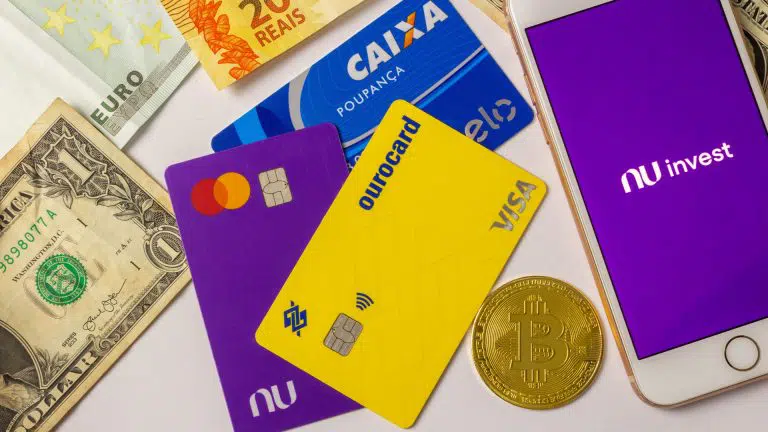 Nota de Real, Dólar e Euro, Cartão Nubank, Caixa e Banco do Brasil, próximo de Bitcoin e aplicativo NuInvest criptomoedas