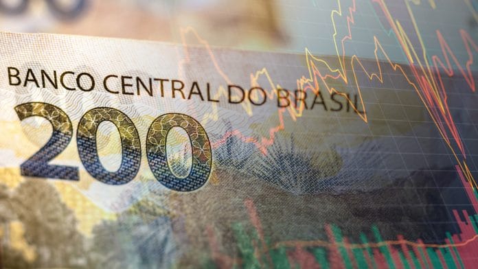 Nota de Real brasileiro com gráfico digital ao lado