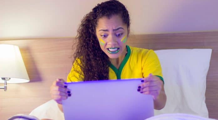 Torcedora brasileira nervosa ao olhar para computador