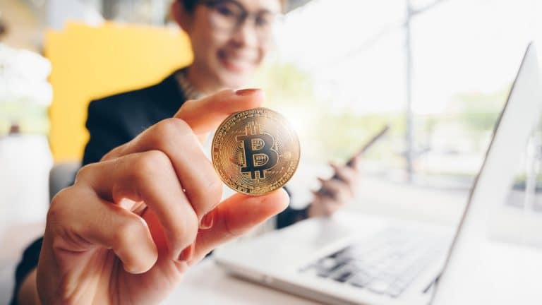 Mulher segurando moeda física de Bitcoin