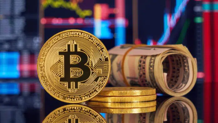 Bitcoin e notas de dólar na frente de telas de gráficos de mercado.