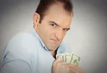homem olhando engraçado segurando notas de dólar com medo de perder dinheiro