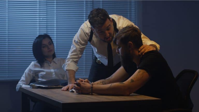 Homem sendo interrogado por políciais.