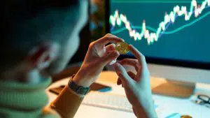 Investidor segurando moeda de Bitcoin