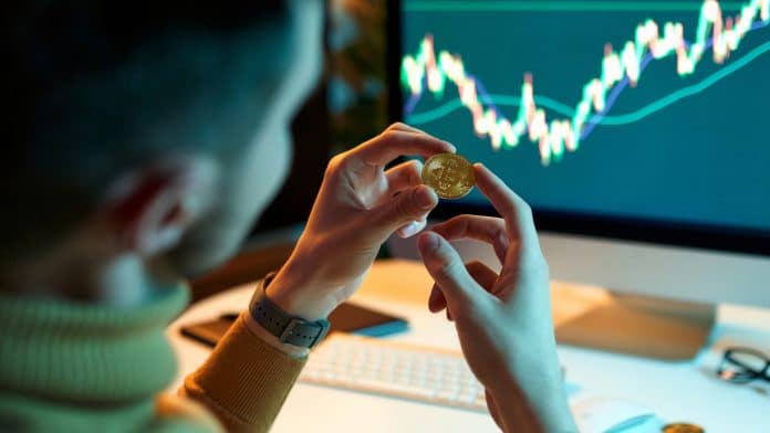 Investidor segurando moeda de Bitcoin
