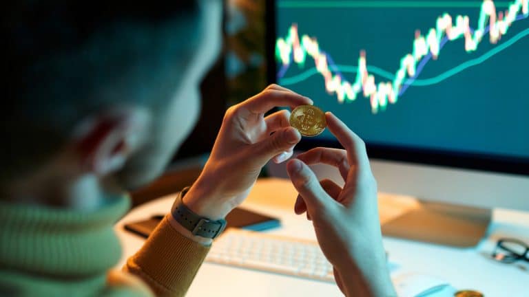 Investidor segurando moeda de Bitcoin