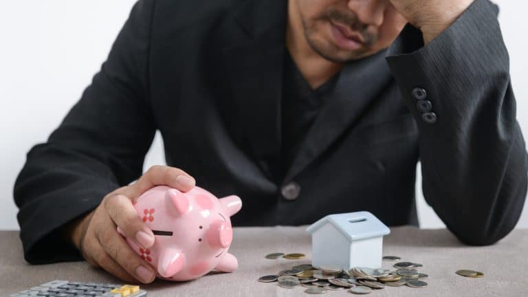Investidor triste contando moedas de seu cofrinho.