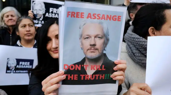 Mulher segurando cartaz em favor da liberdade de Julian Assange