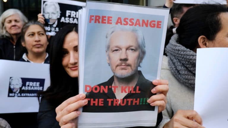 Mulher segurando cartaz em favor da liberdade de Julian Assange
