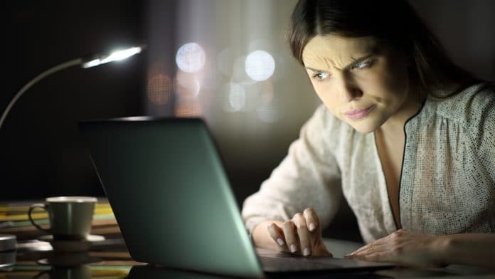 Mulher desconfiada ao ler e-mail