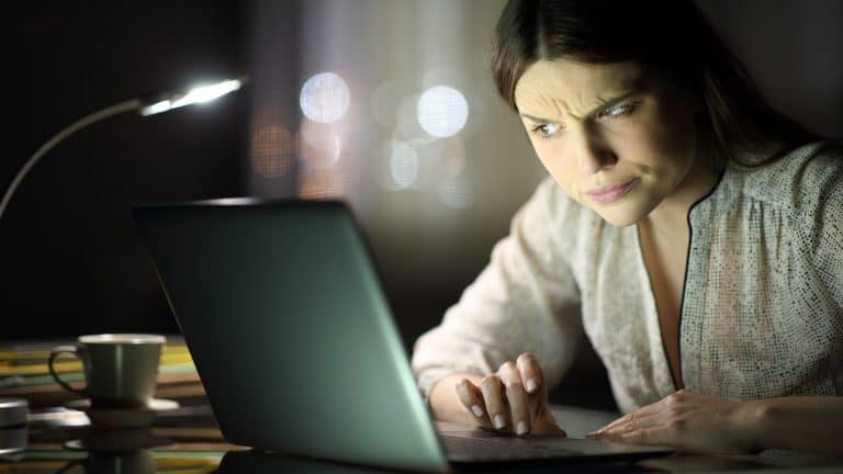 Mulher desconfiada ao ler e-mail