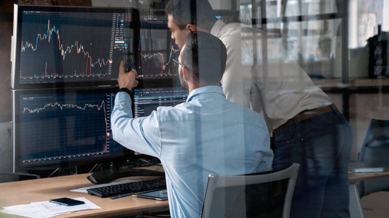 Traders acompanhando gráficos de preço.