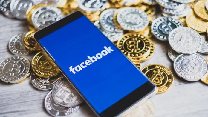 Aplicativo do Facebook ao lado de moedas de Bitcoin