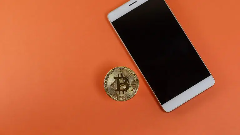 Bitcoin ao lado de aparelho celular comprar criptomoedas