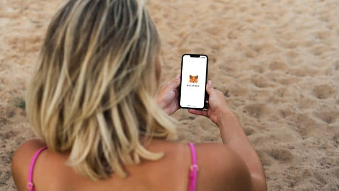 Garota na praia usando sua carteira MetaMask