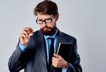 Homem curioso com óculos examina criptomoeda Bitcoin
