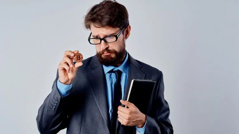 Homem curioso com óculos examina criptomoeda Bitcoin