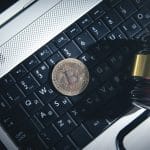 Martelo da justiça em cima de notebook e ao lado de Bitcoin