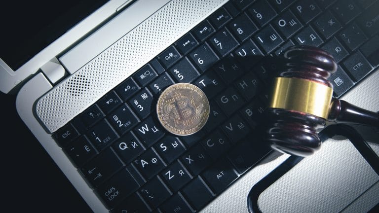 Martelo da justiça em cima de notebook e ao lado de Bitcoin