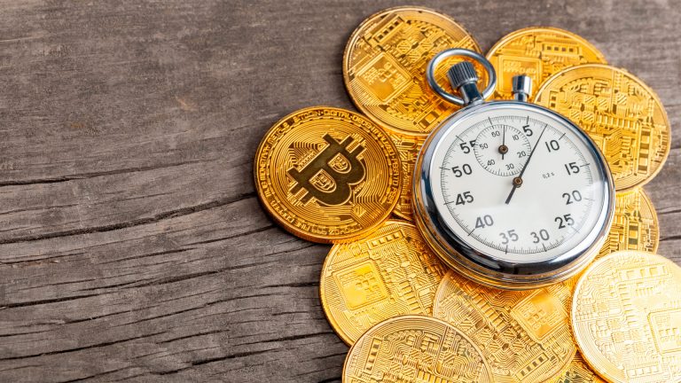 Moedas de Bitcoin ao lado de cronômetro.
