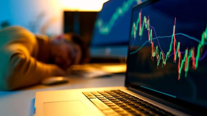 Usuário de Bitcoin dormindo em frente ao computador com gráfico subindo.