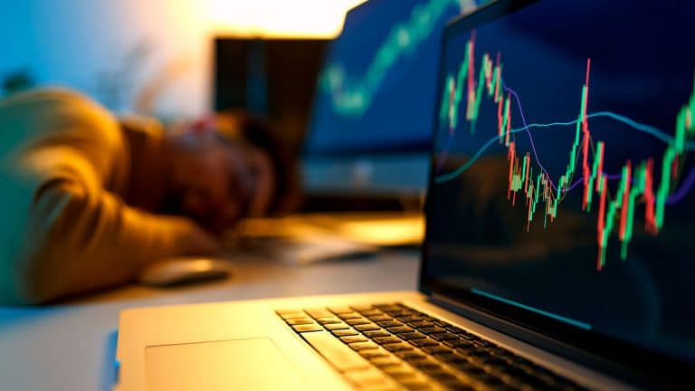 Usuário de Bitcoin dormindo em frente ao computador com gráfico subindo.