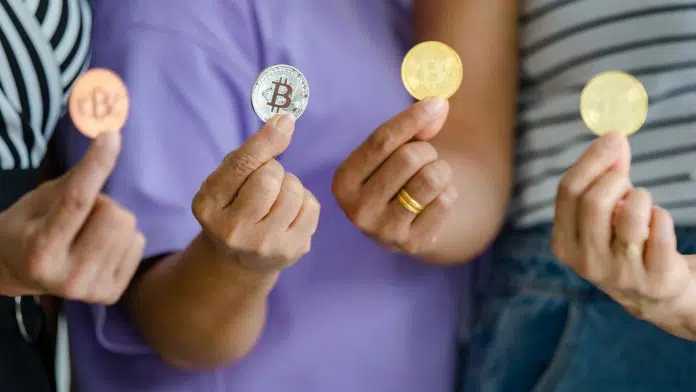 Quatro pessoas segurando moedas físicas de Bitcoin.