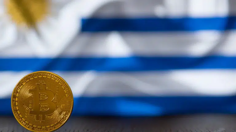 Bitcoin em frente a bandeira do Uruguai ao fundo