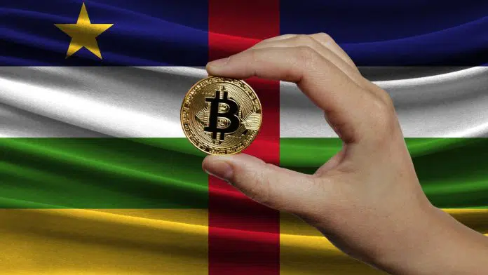 Mão segurando bitcoin com bandeira da República Centro-Africana ao fundo