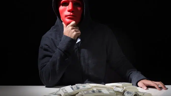 Mascarado próximo de pilha de dinheiro