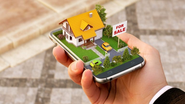 Miniatura de casa em tela de celular, assunto de metaverso e imóveis