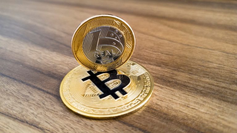 Moeda de 1 real em cima de Bitcoin bancos e criptomoedas