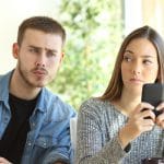 Mulher com olhar desconfiado para homem ao seu lado