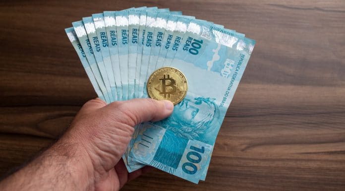 Notas de real e bitcoin em mão