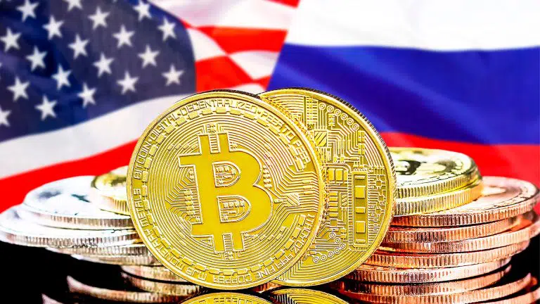 Moedas de Bitcoin entre bandeiras da Rússia e EUA.