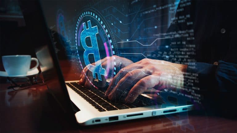 Pessoa usando notebook com logotipo do Bitcoin em forma holográfica.