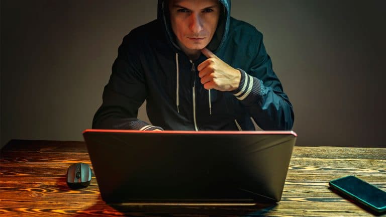 Homem usando notebook com más intenções.
