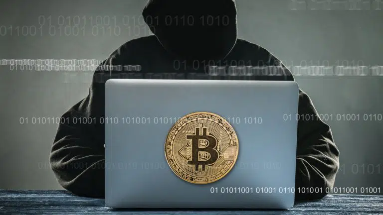 Hacker com computador com imagem do bitcoin